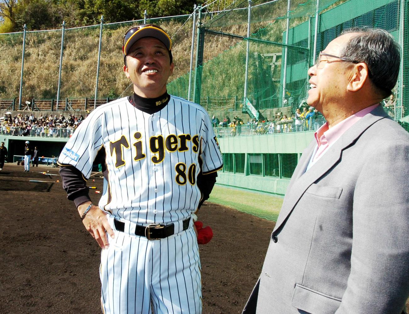 08年、阪神春季キャンプ　安芸市営球場のグラウンドで笑顔を見せる吉田氏（右）と岡田監督