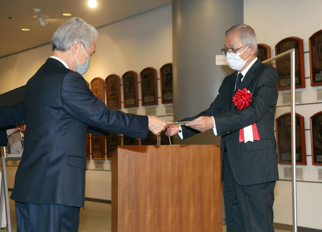 榊原コミッショナー（左）から野球殿堂入り通知書を受け取る、古関さん長男の正裕氏（代表撮影）