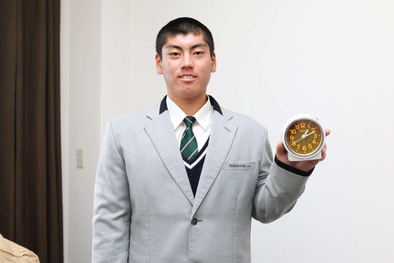 1月6日の入寮時に、持参した目覚まし時計を手に笑顔の楽天古賀（楽天野球提供）