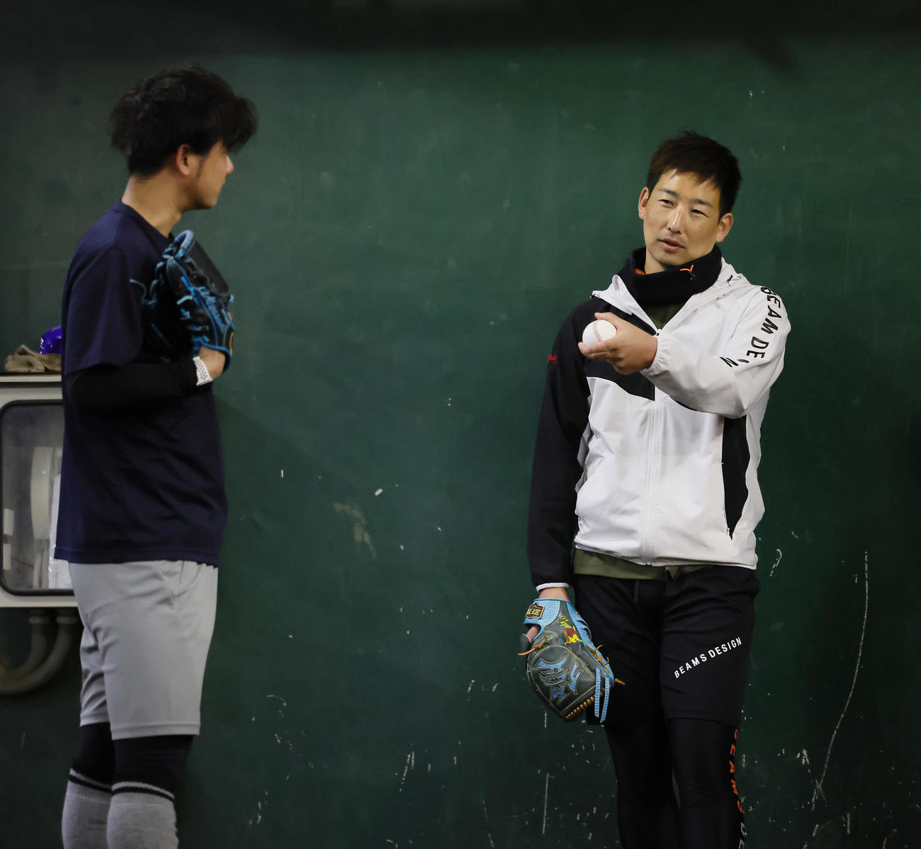 自主トレのブルペンで投球について話す阪神川原（左）と岩崎（撮影・足立雅史）
