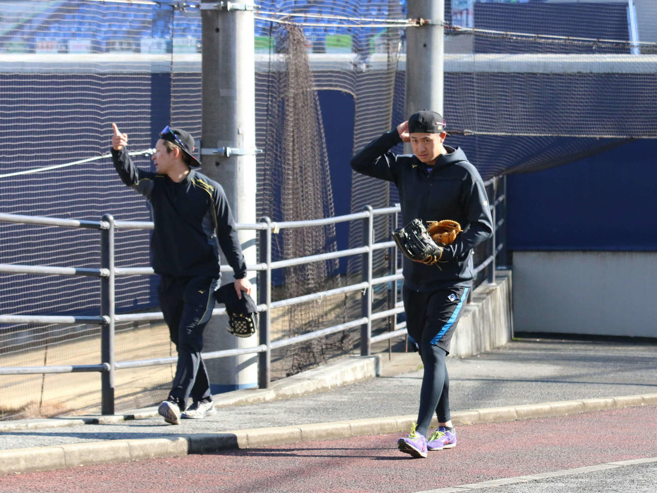 内外野用のグラブを2つ持って寮へ引き揚げる日本ハム阪口（右）（撮影・中島宙恵）
