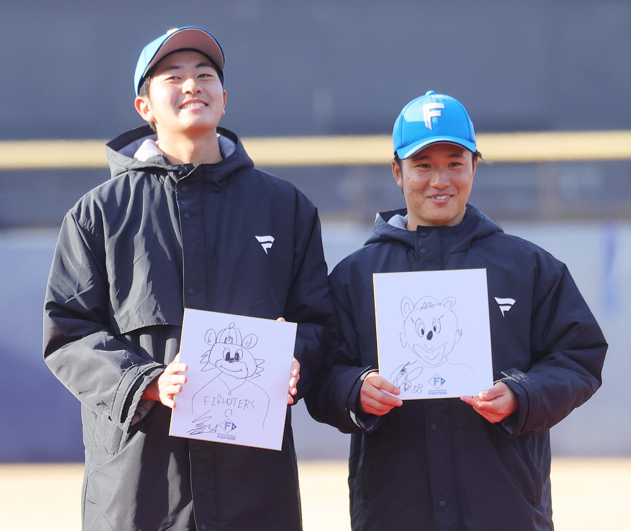 新人お披露目会での似顔絵コンテストで、マスコットのコビーの絵を披露する日本ハム安西（左）と奈良間（撮影・野上伸悟）