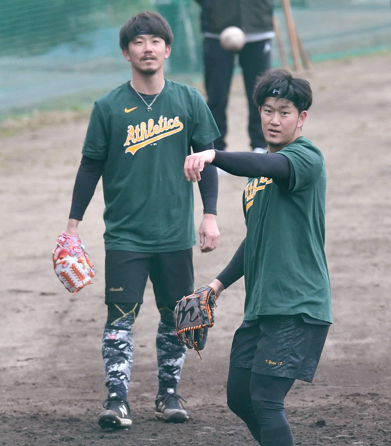 アスレチックスのTシャツを着てノックを受ける岩貞（右）と伊藤将（撮影・岩下翔太）