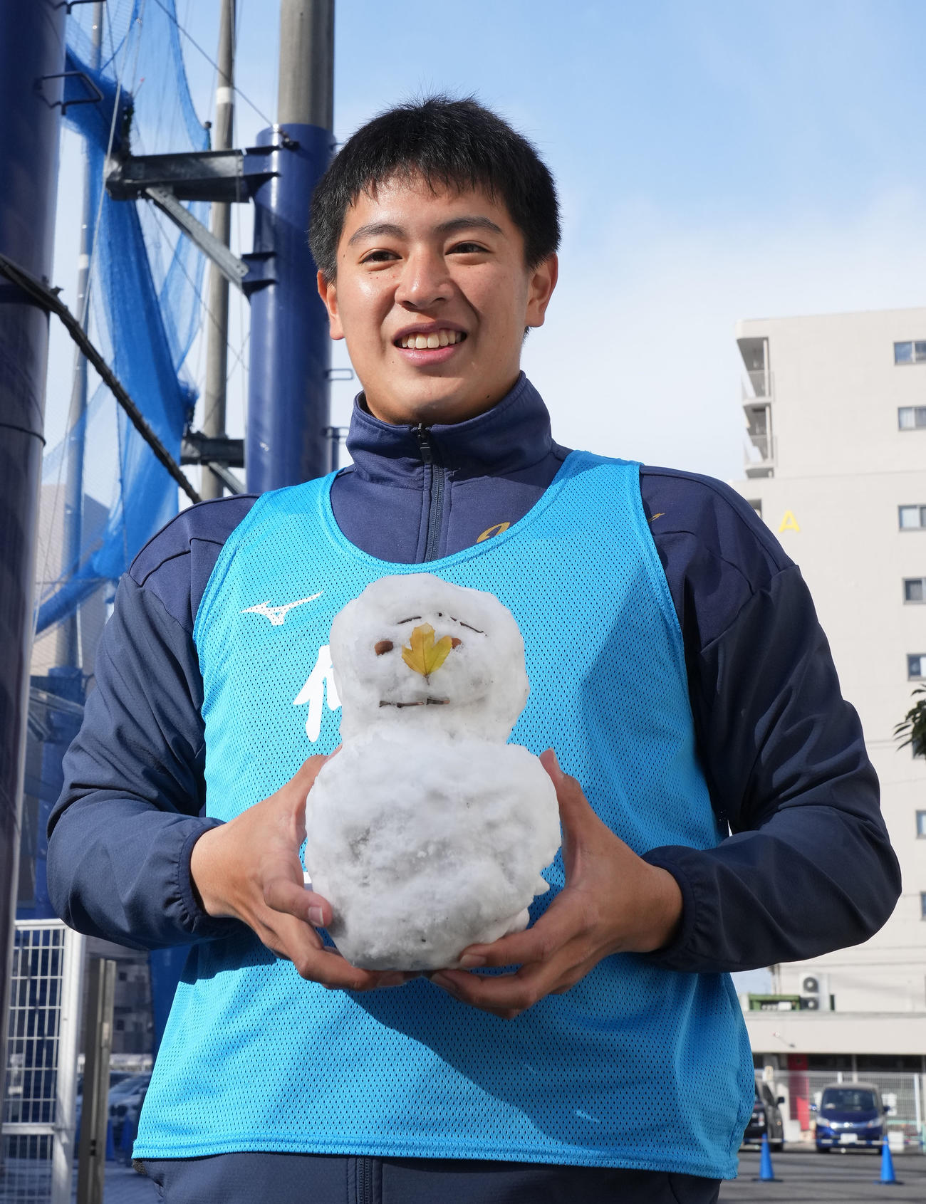 報道陣が作成した雪だるまを手に明るい表情を見せる仲地（撮影・森本幸一）