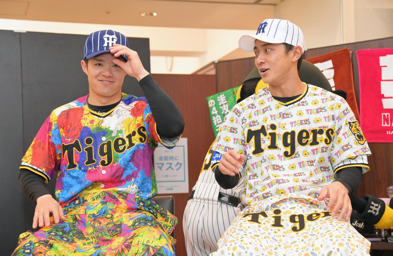 新作グッズの紹介でデザインユニホームを着用する阪神中野（左）と熊谷