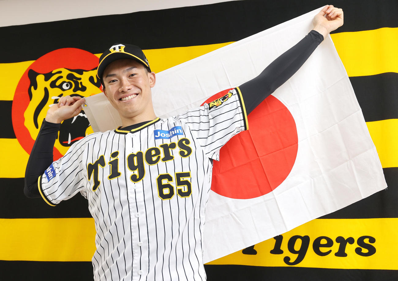 阪神湯浅は侍ジャパンに選出され、日の丸を背に笑顔を見せる（撮影・上山淳一）