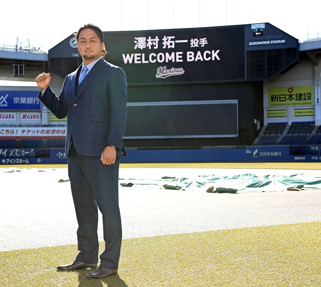 「WELCOME BACK」のボードを背にポーズを決めるロッテ沢村（撮影・たえ見朱実）