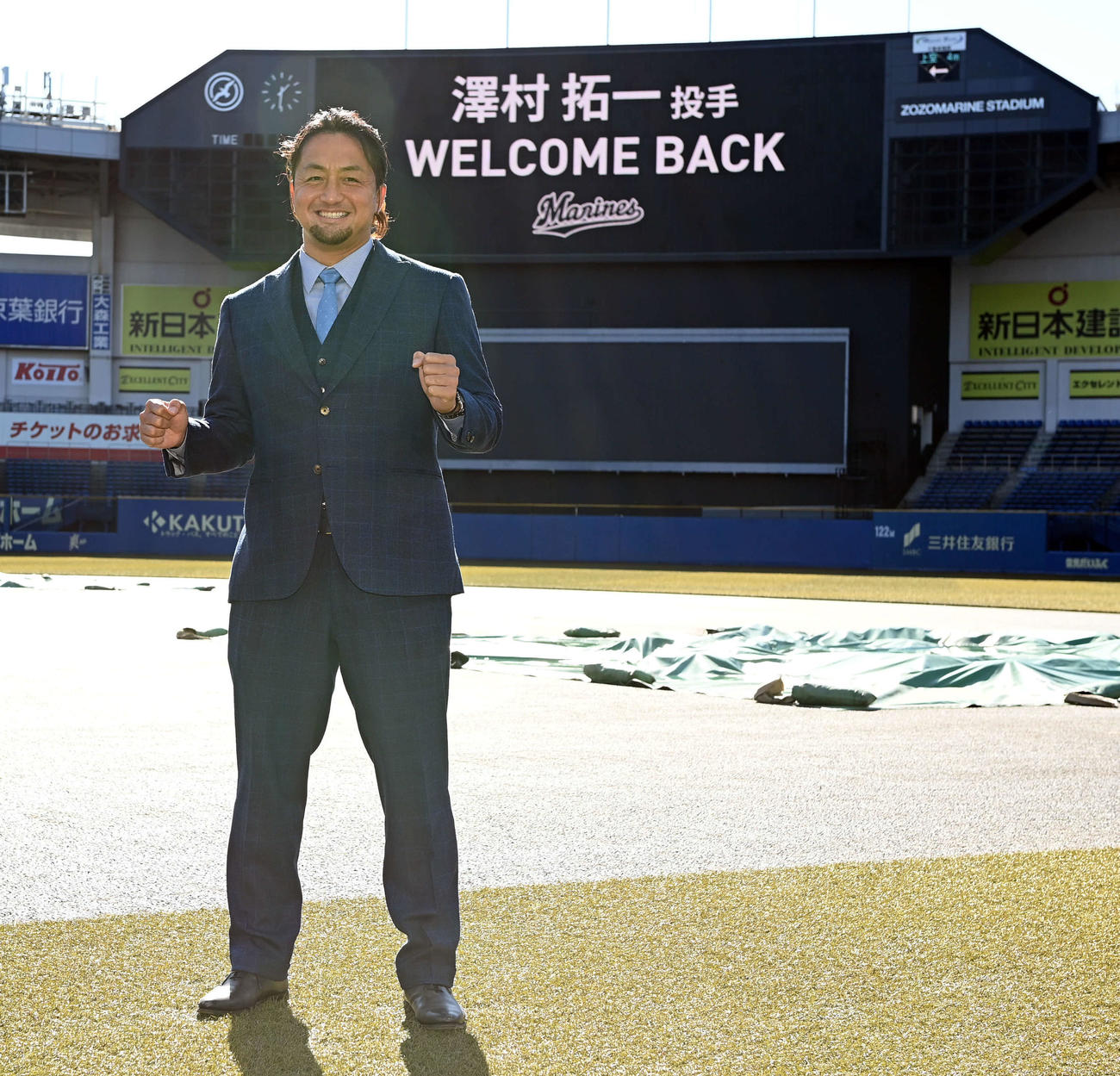 「WELCOME BACK」のボードを背にポーズを決めるロッテ沢村（撮影・たえ見朱実）