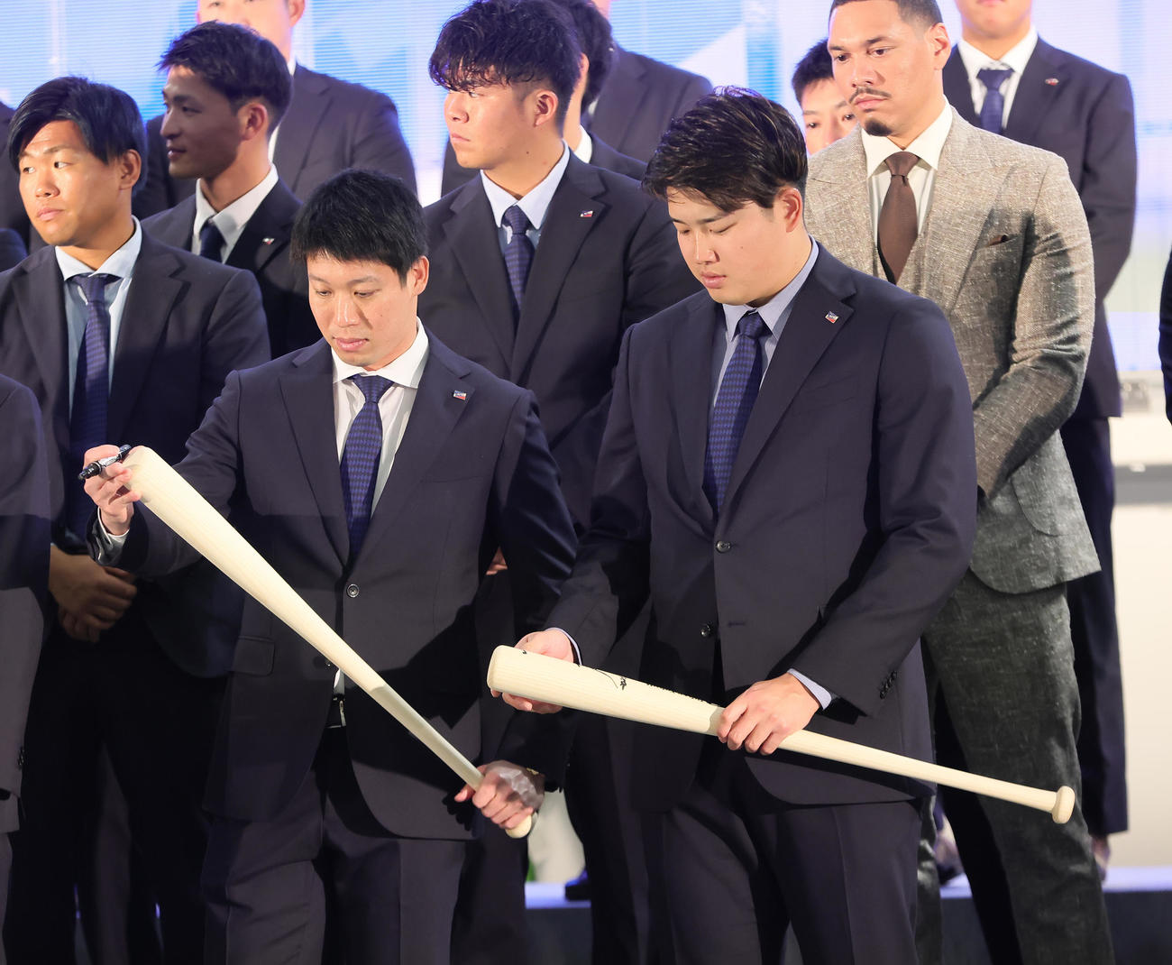 歓迎セレモニーでファンにプレゼントするバットを見つめる山田（左）と村上（撮影・足立雅史）