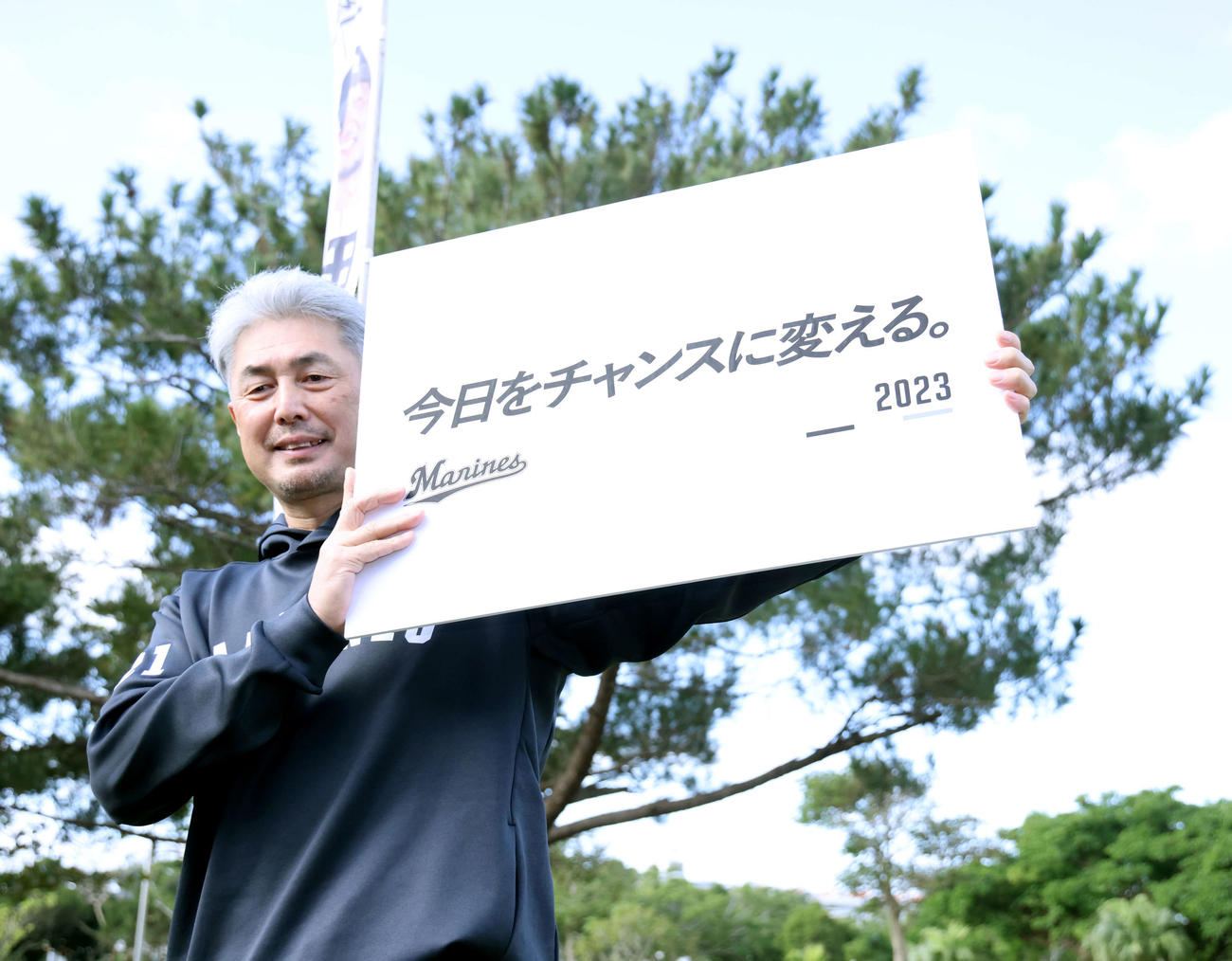 スローガンのボードを手に写真に納まるロッテ吉井監督（撮影・河田真司）