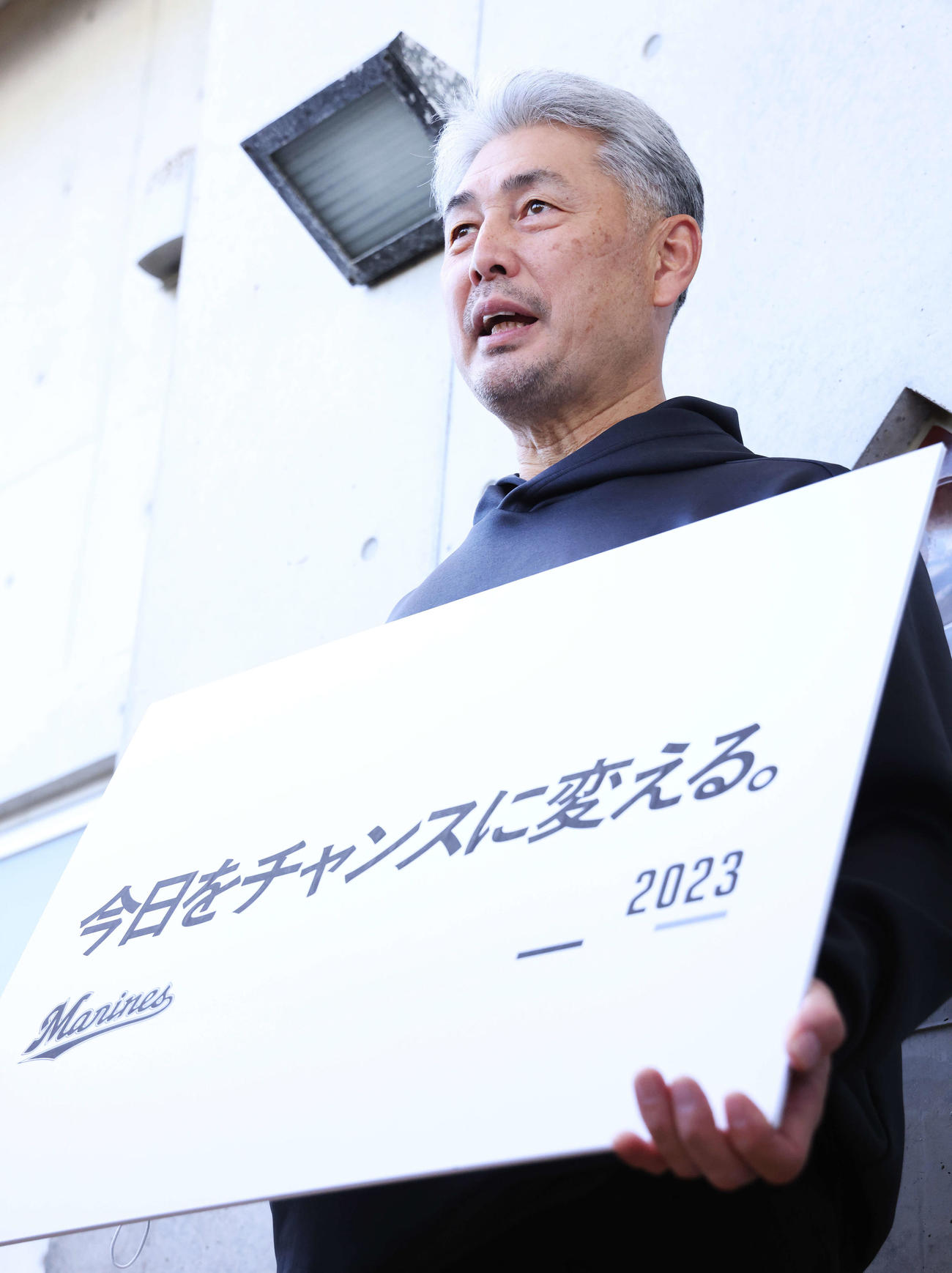 スローガンのボードを手に記者の質問に答えるロッテ吉井監督（撮影・河田真司）