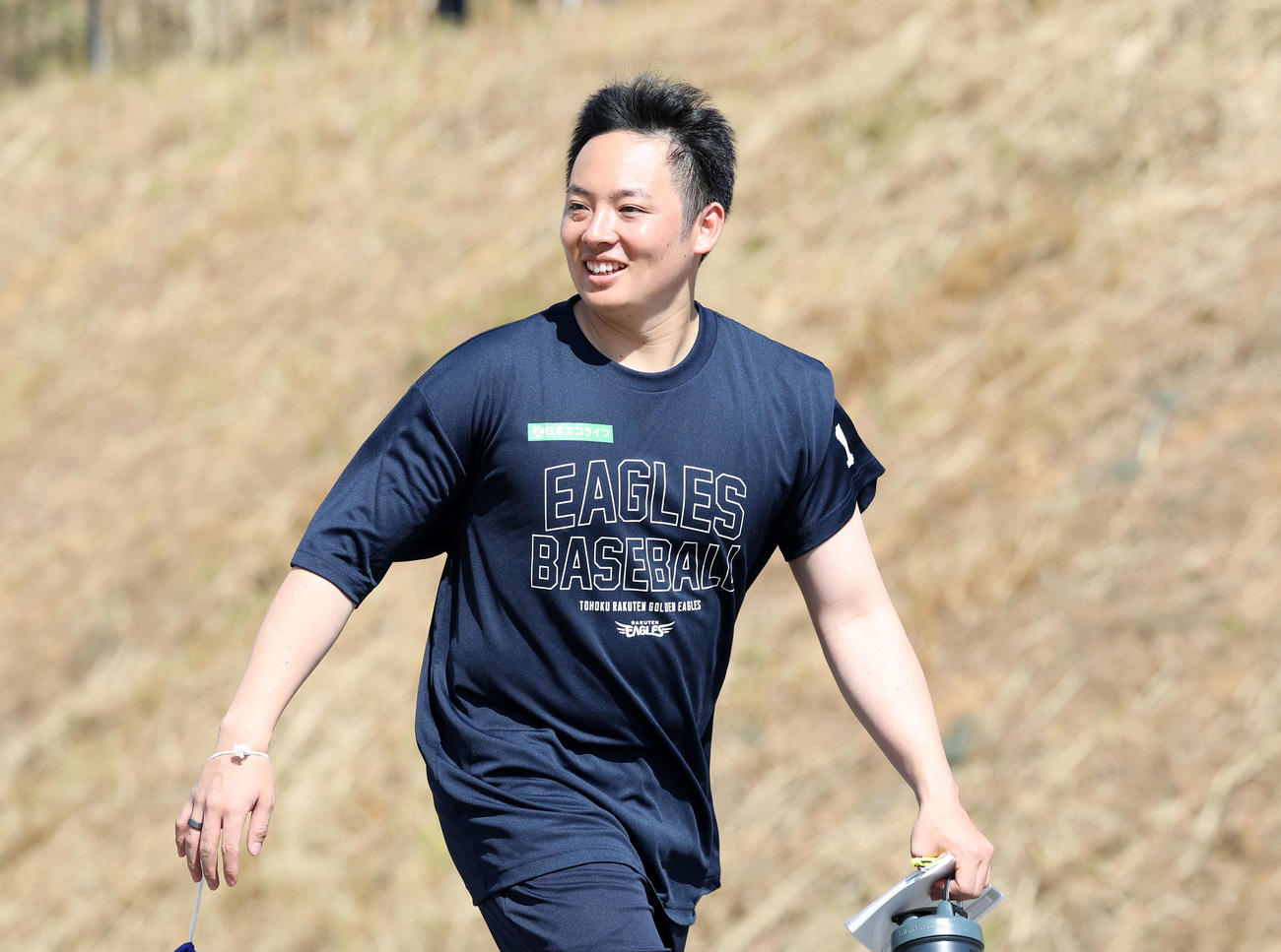 移動中、カメラマンに笑顔を見せる楽天松井裕（撮影・鈴木正人）