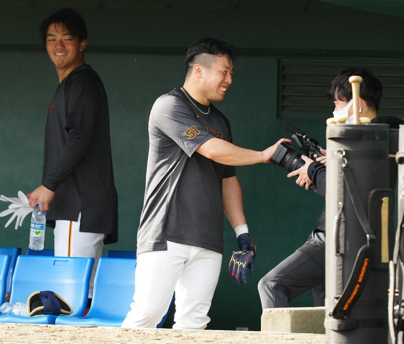 練習中、ビデオカメラのレンズを手でふさぎ、笑顔を見せる巨人浅野（中央）（撮影・江口和貴）