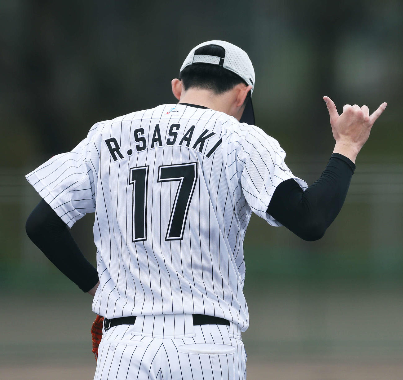 投内連係でナインの掛け声にポーズするロッテ佐々木朗（撮影・河田真司）