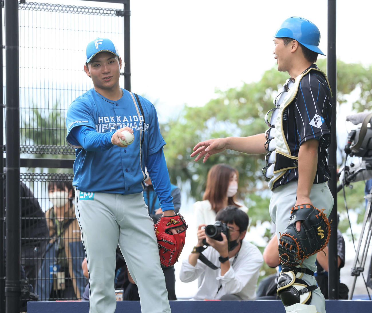 ブルペンで投球後、捕手を務めた伏見（右）と話す日本ハム伊藤（撮影・黒川智章）