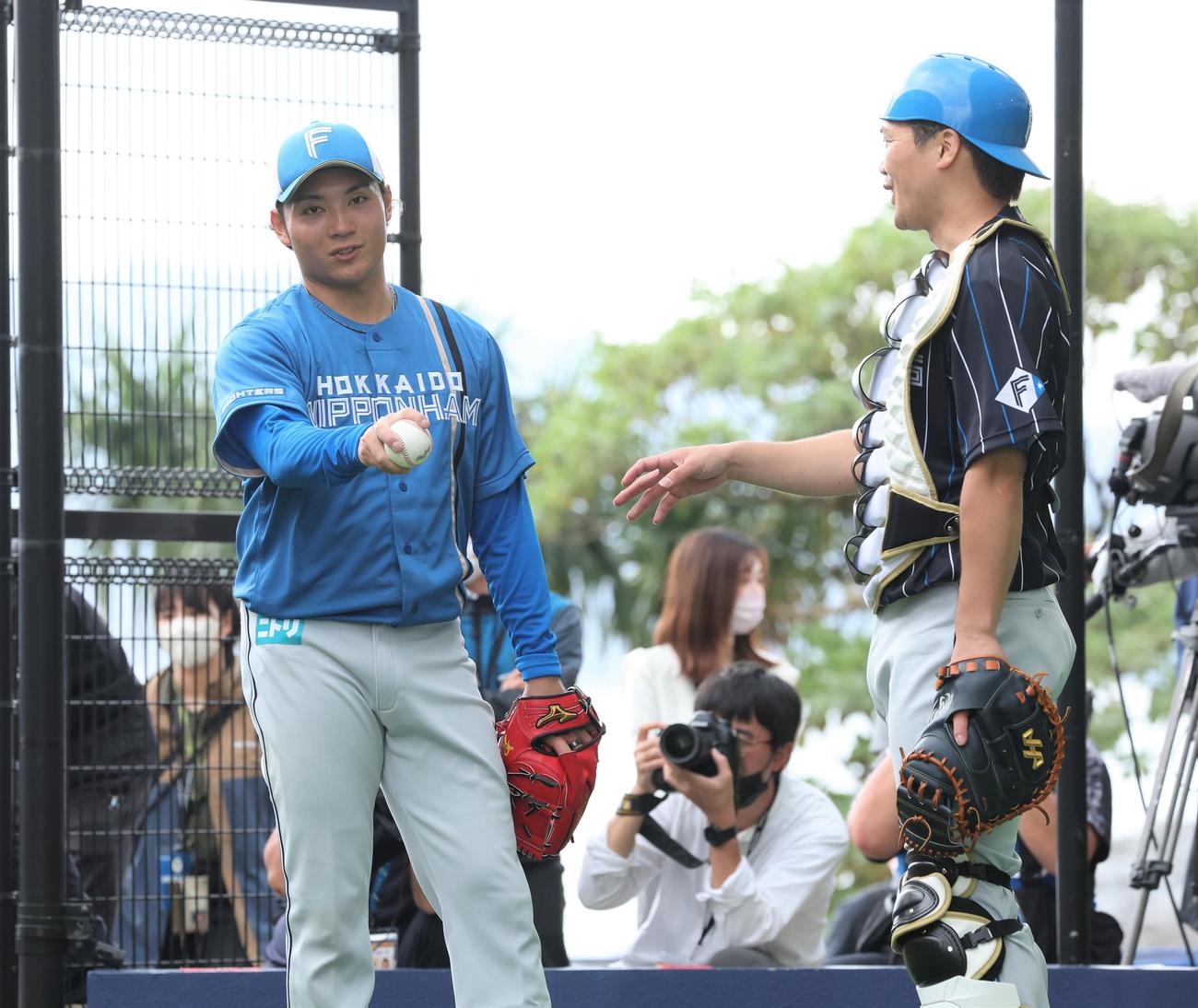 ブルペンで投球後、捕手を務めた伏見（右）と話す日本ハム伊藤（撮影・黒川智章）