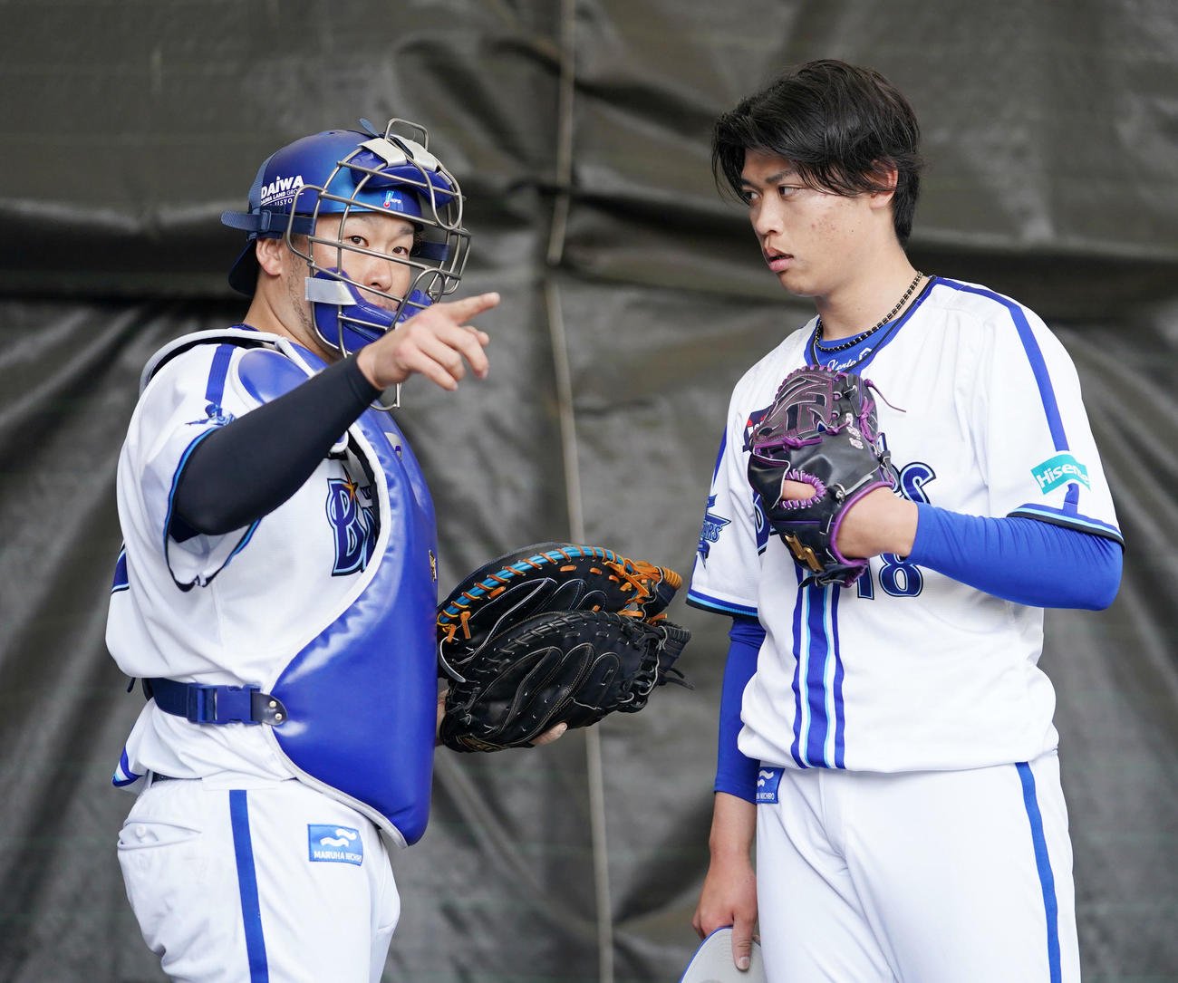 ブルペンで言葉を交わすDeNA戸柱（左）と小園（撮影・横山健太）