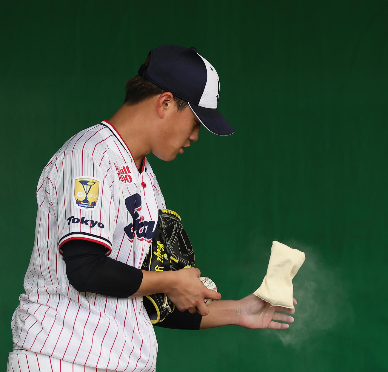 WBC公式球でブルペン投球するヤクルト高橋は手にロジンをつける（撮影・足立雅史）