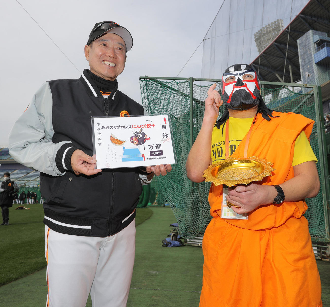 激励に訪れたザ・グレート・サスケ（右）から餃子の目録を受け取った巨人原監督