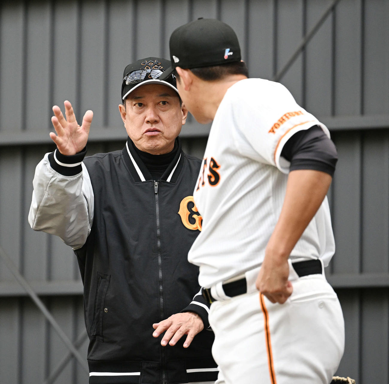 ブルペンで投球練習する巨人菅野（手前）と話す原監督（撮影・滝沢徹郎）