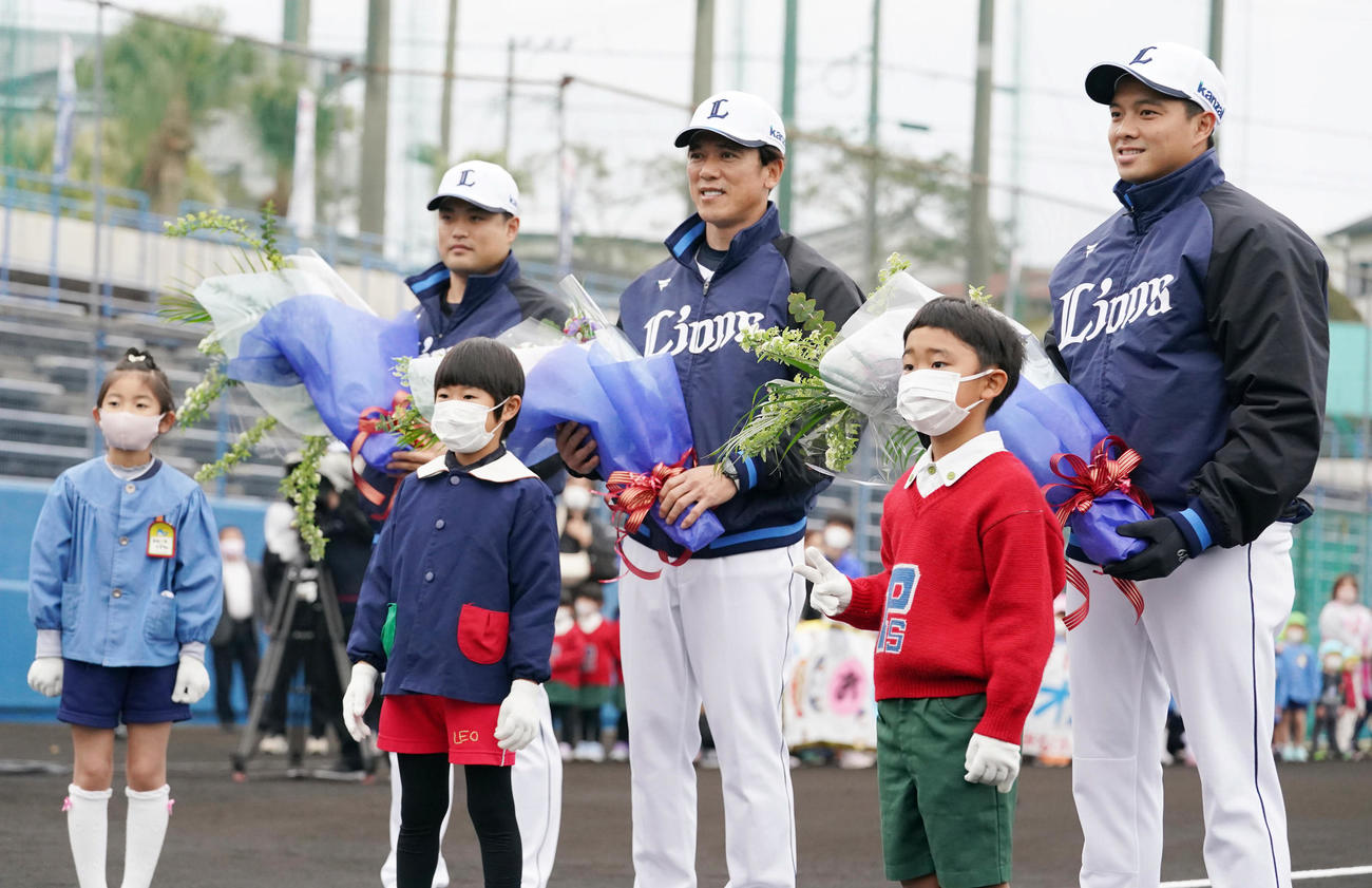 南郷キャンプ初日を迎え歓迎セレモニーで子どもたちから花束贈呈を受ける、左から西武松本、松井監督、呉念庭（撮影・小沢裕）