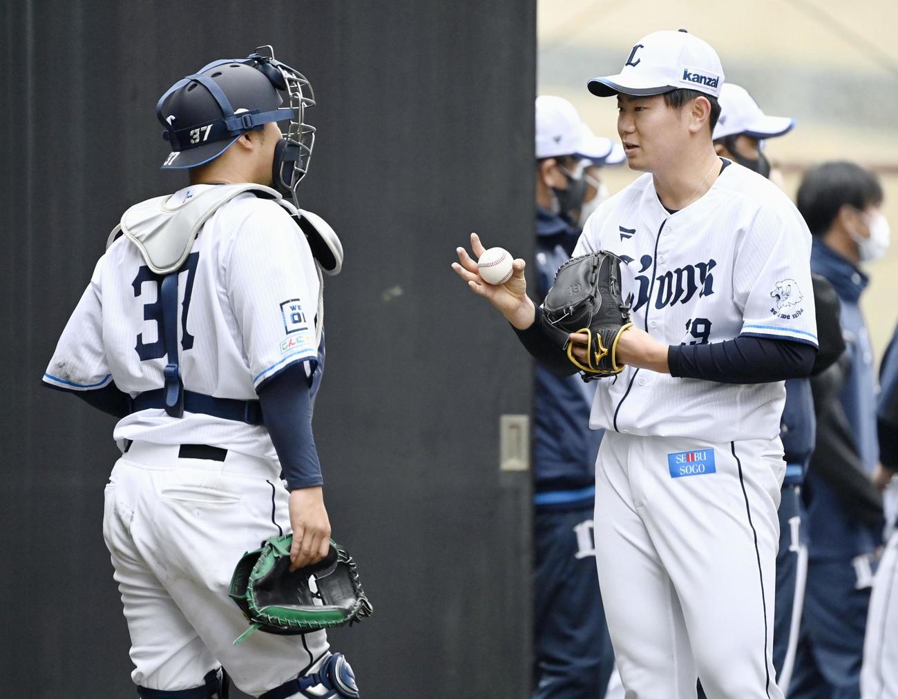 ブルペンでの投球練習後、捕手の柘植（左）と話す西武ドラフト4位新人の青山（共同）