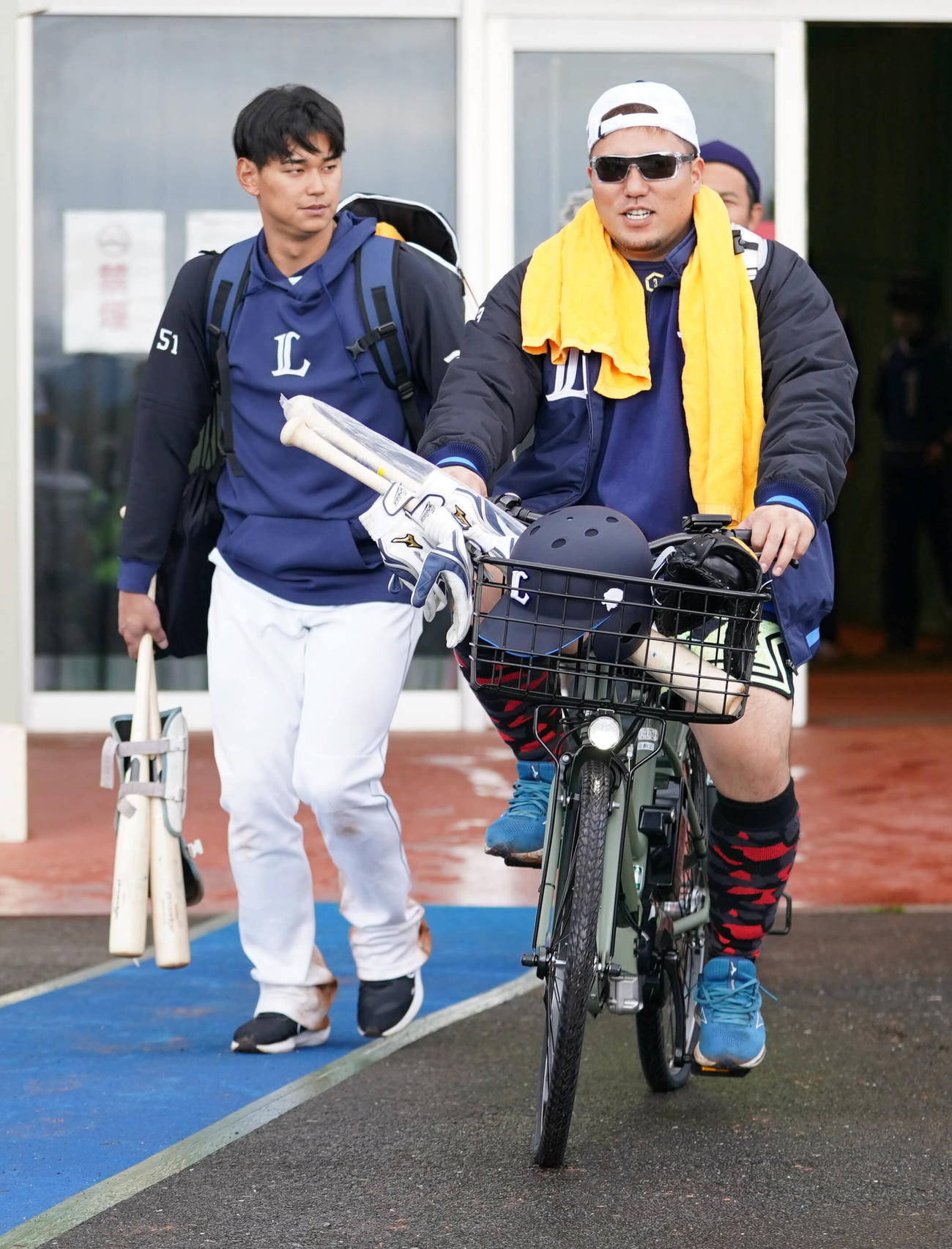 練習を終えた西武山川は電動自転車に乗って室内練習場をあとにする。後方左は西川（撮影・小沢裕）