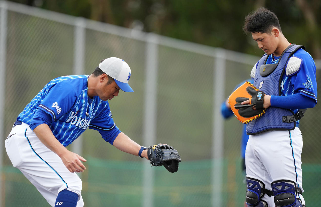 DeNA相川チーフ作戦兼バッテリーコーチ（左）から指導を受ける松尾（撮影・横山健太）