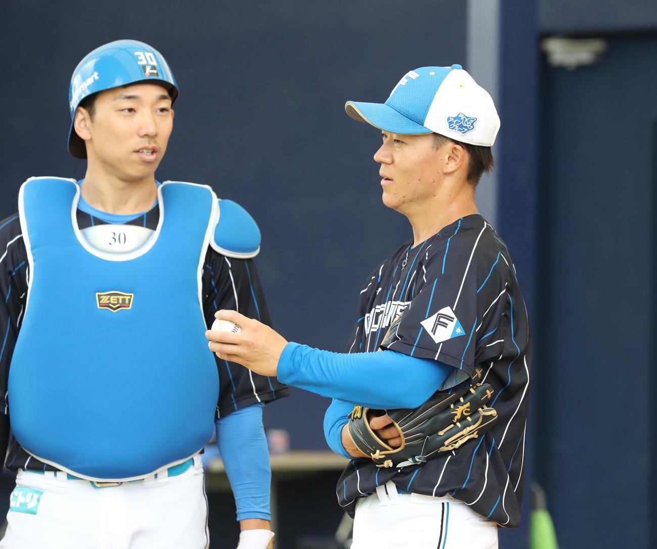 ブルペンで投球後、宇佐見（左）と話す日本ハム矢沢（撮影・黒川智章）