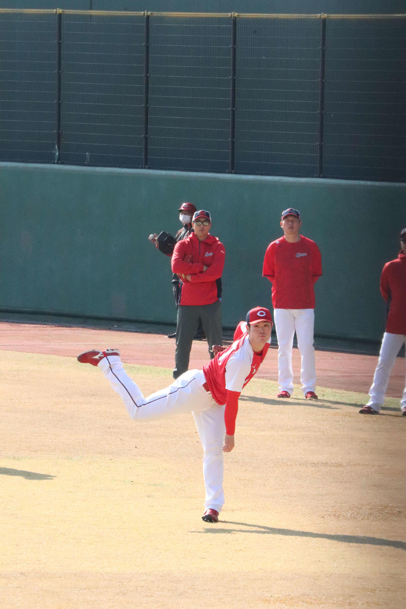 黒田博樹球団アドバイザーと新井貴浩監督（後方左から）が見つめる中、キャッチボールする広島ドラフト1位斉藤優汰投手（2023年2月8日撮影）