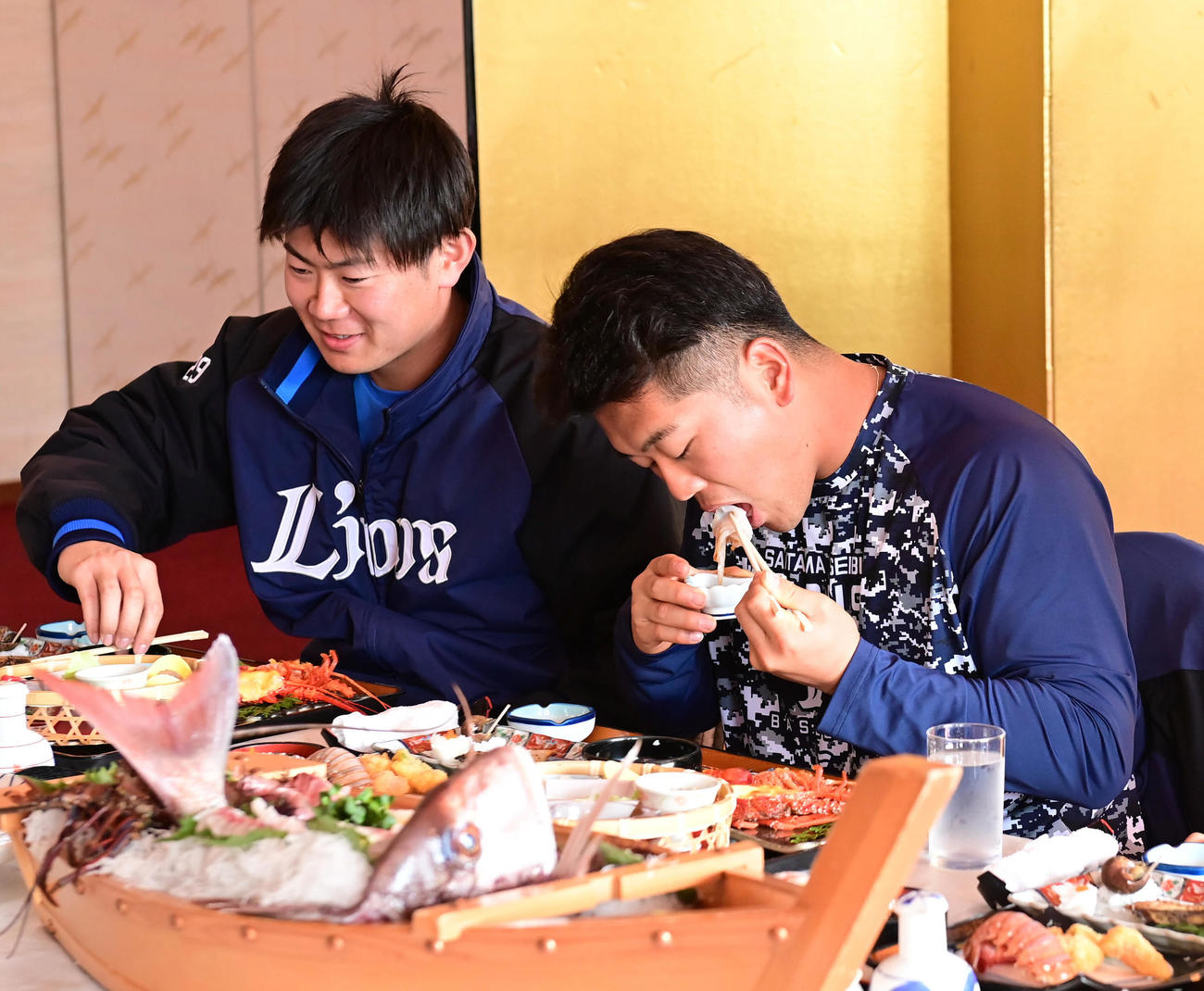 キャンプはじめての休日で昼食の海鮮料理にふぐ刺しを食べる西武蛭間拓哉。左は青山（撮影・小沢裕）