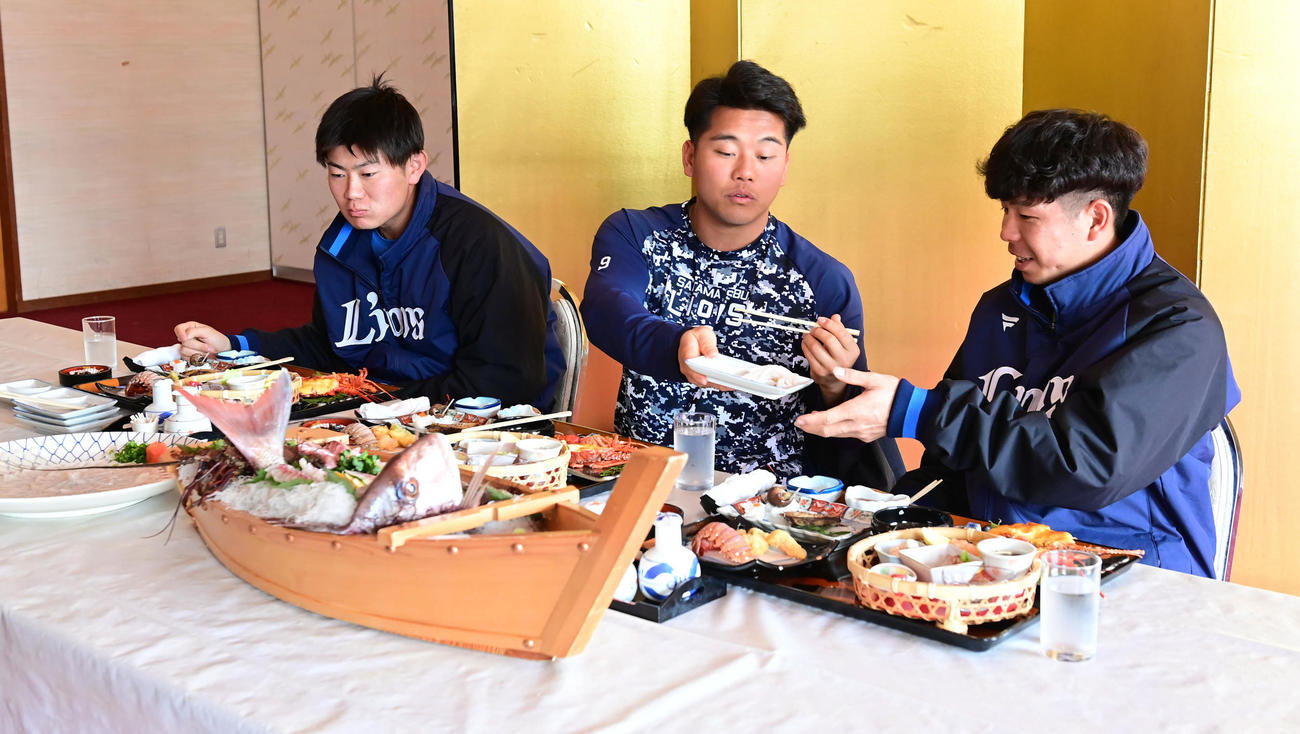キャンプはじめての休日で昼食の海鮮料理でふぐ刺しを食べる、左から西武青山、蛭間、児玉（撮影・小沢裕）
