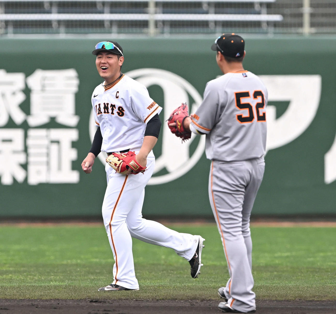 巨人紅白戦前に左翼でシートノックを受けた岡本和（左）は笑顔を見せる（撮影・滝沢徹郎）