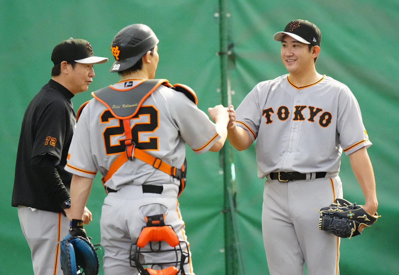 ブルペン投球を終え、巨人捕手小林（中央）とタッチを交わす菅野。左は阿波野投手チーフコーチ（撮影・江口和貴）
