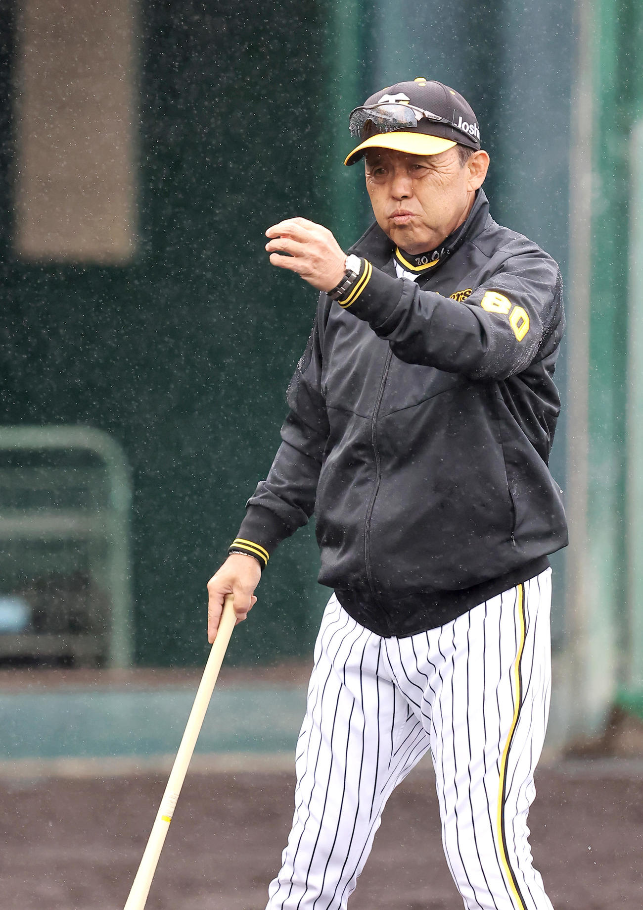 雨の中、グラウンドで練習を見る岡田監督（撮影・上山淳一）