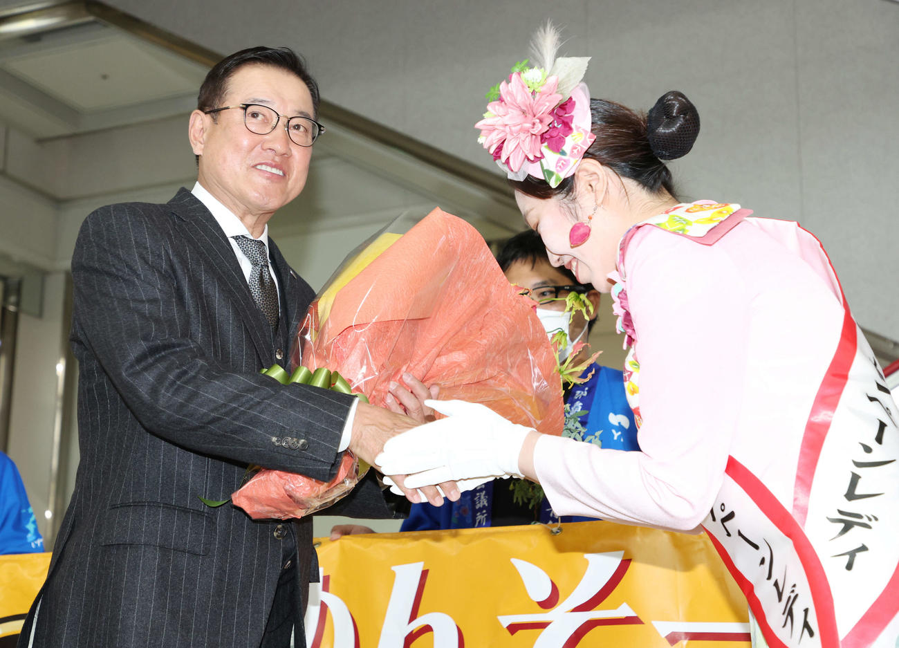 那覇空港での歓迎セレモニーで、那覇観光キャンペーンレディ（右）から花束を受け取り握手する巨人原監督（撮影・宮地輝）