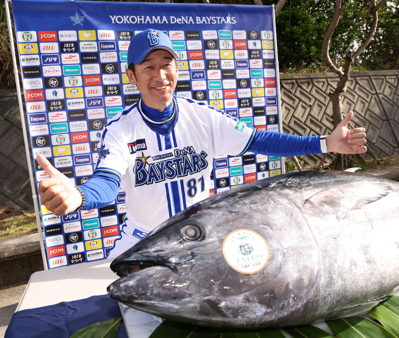 マルハニチロから養殖クロマグロが贈呈され、サムズアップで写真に納まるDeNA三浦監督（撮影・河田真司）