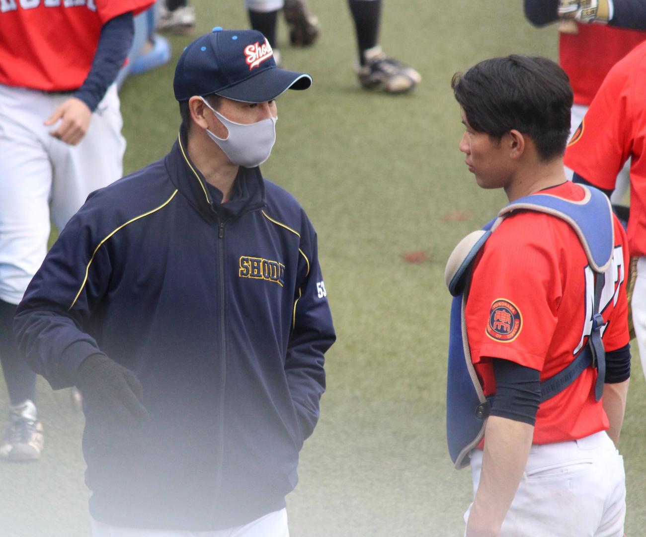 イニング間に選手に声をかける横浜商大・須田コーチ（左）（撮影・保坂恭子）