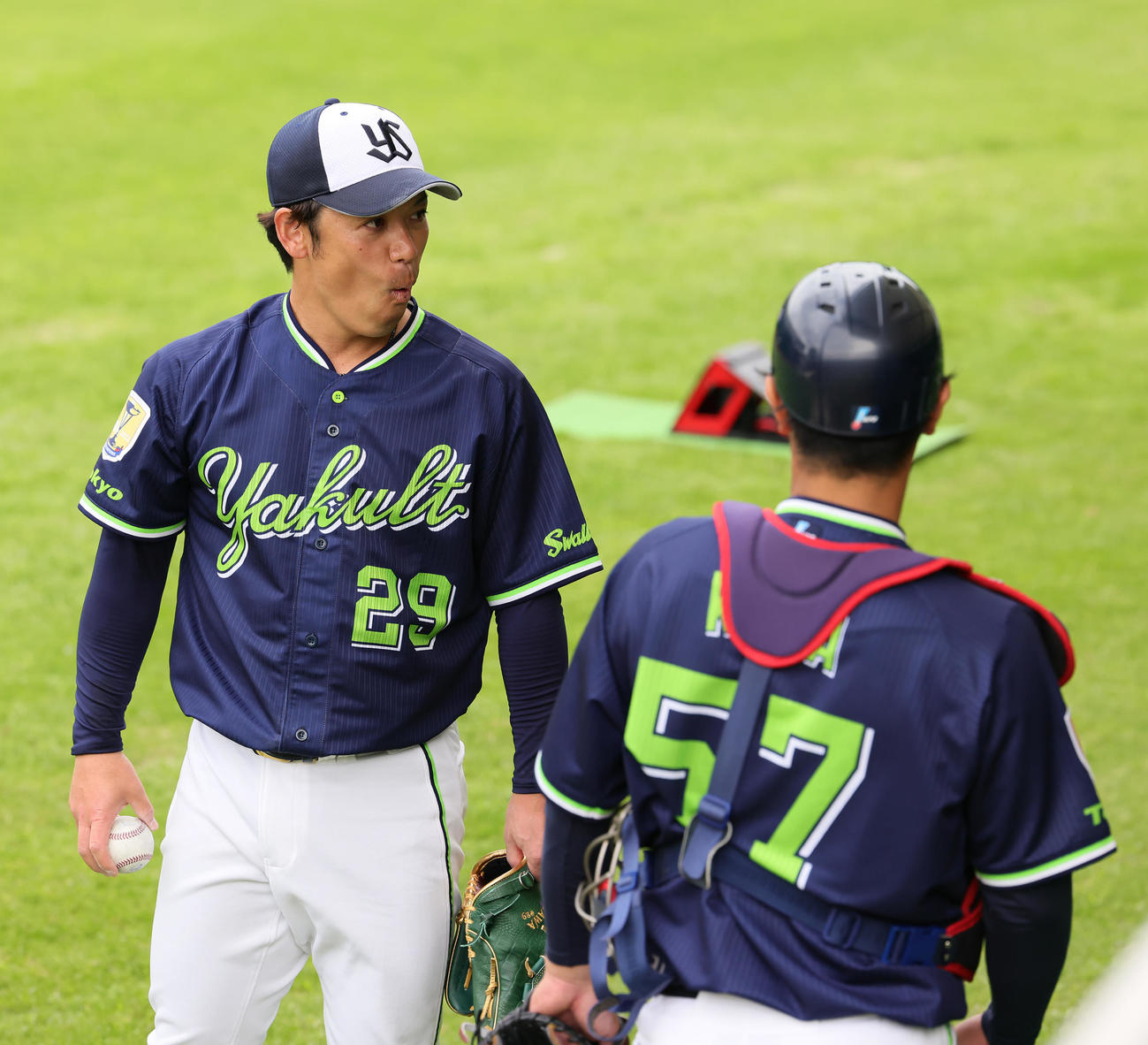 ブルペン投球を終えたヤクルト小川（左）は驚いた様な表情でおどける（撮影・足立雅史）