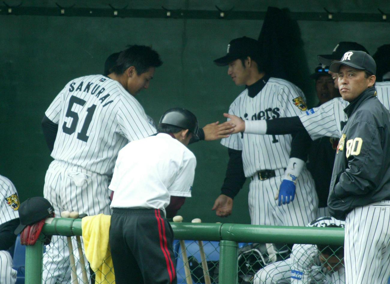 2004年オープン戦　阪神対オリックス　7回裏1死満塁、中越えに走者一掃の逆転二塁打を放った桜井広大はベンチで祝福を受ける。右は岡田彰布監督（2004年2月28日撮影）