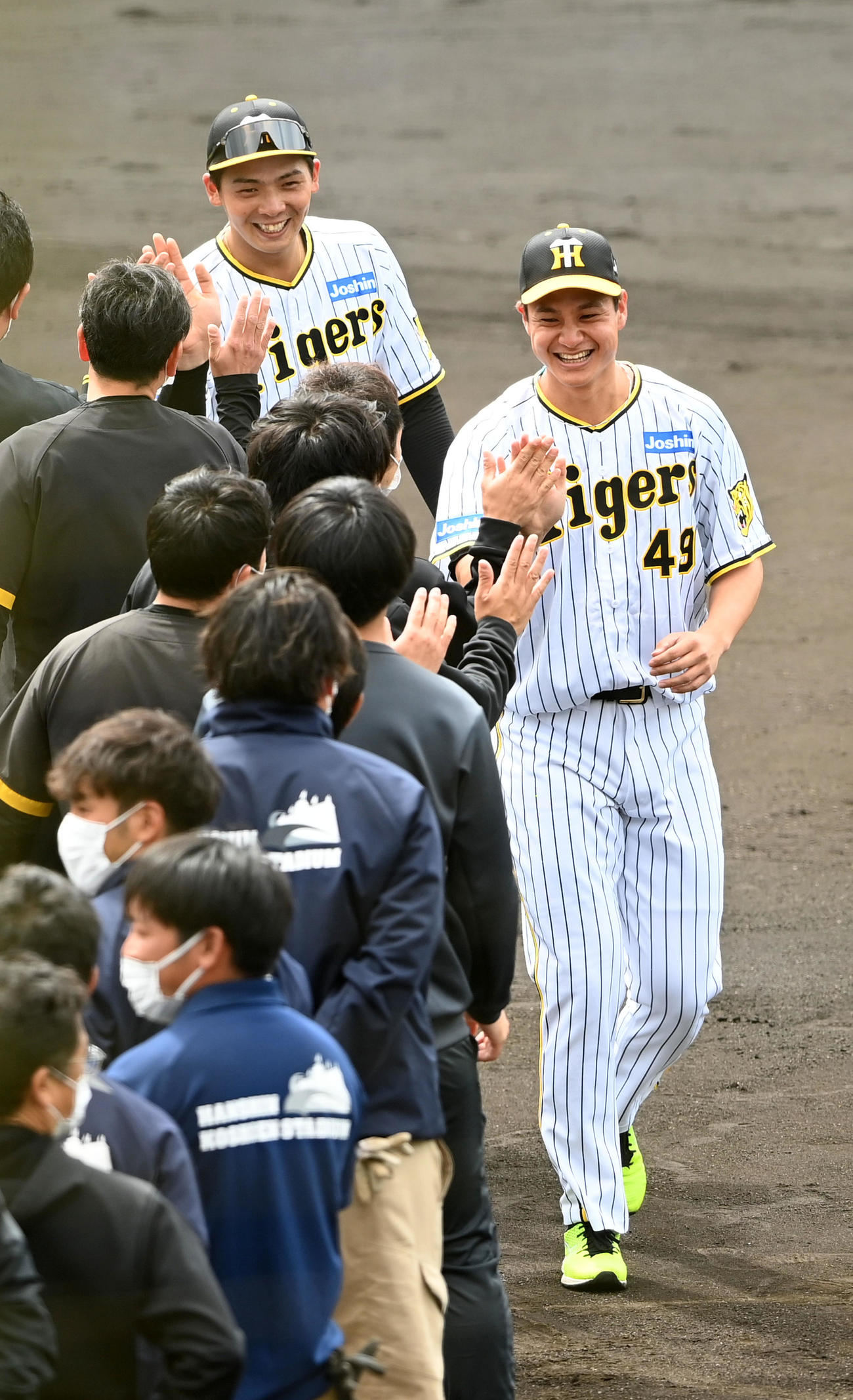 キャンプを終え、笑顔でスタッフらとタッチする阪神大竹（手前）と井上（撮影・前岡正明）