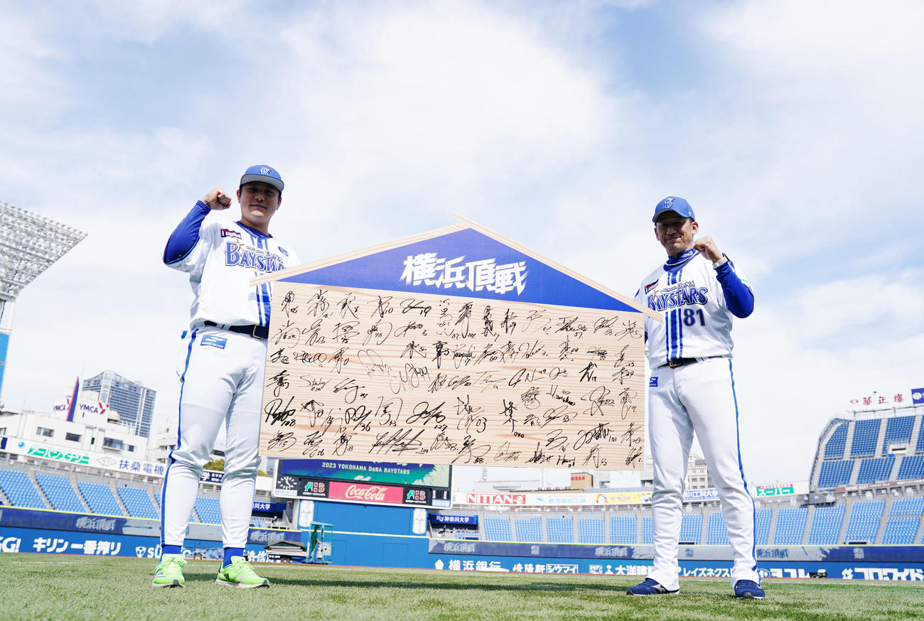 巨大絵馬を手に笑顔でガッツポーズするDeNA佐野（左）と三浦監督（撮影・横山健太）
