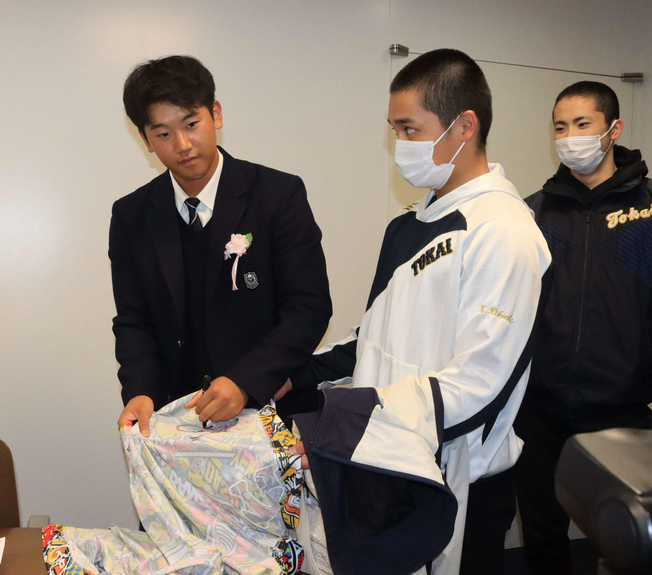 卒業式後、後輩にサインを求められ対応する阪神ドラフト2位の門別（左）（撮影・保坂果那）