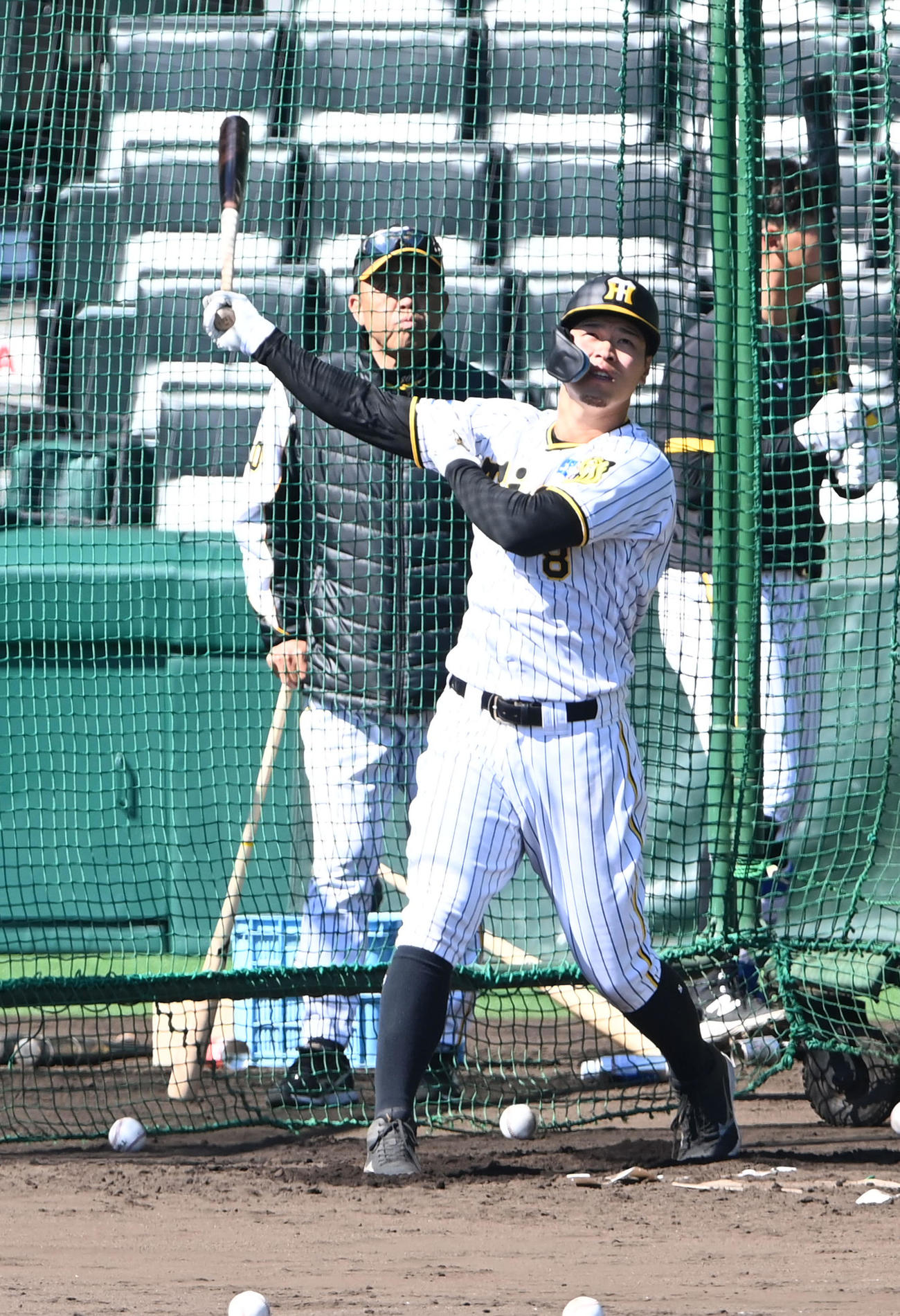 岡田監督（後方）が見守る中、打撃練習を行う佐藤輝（撮影・前岡正明）