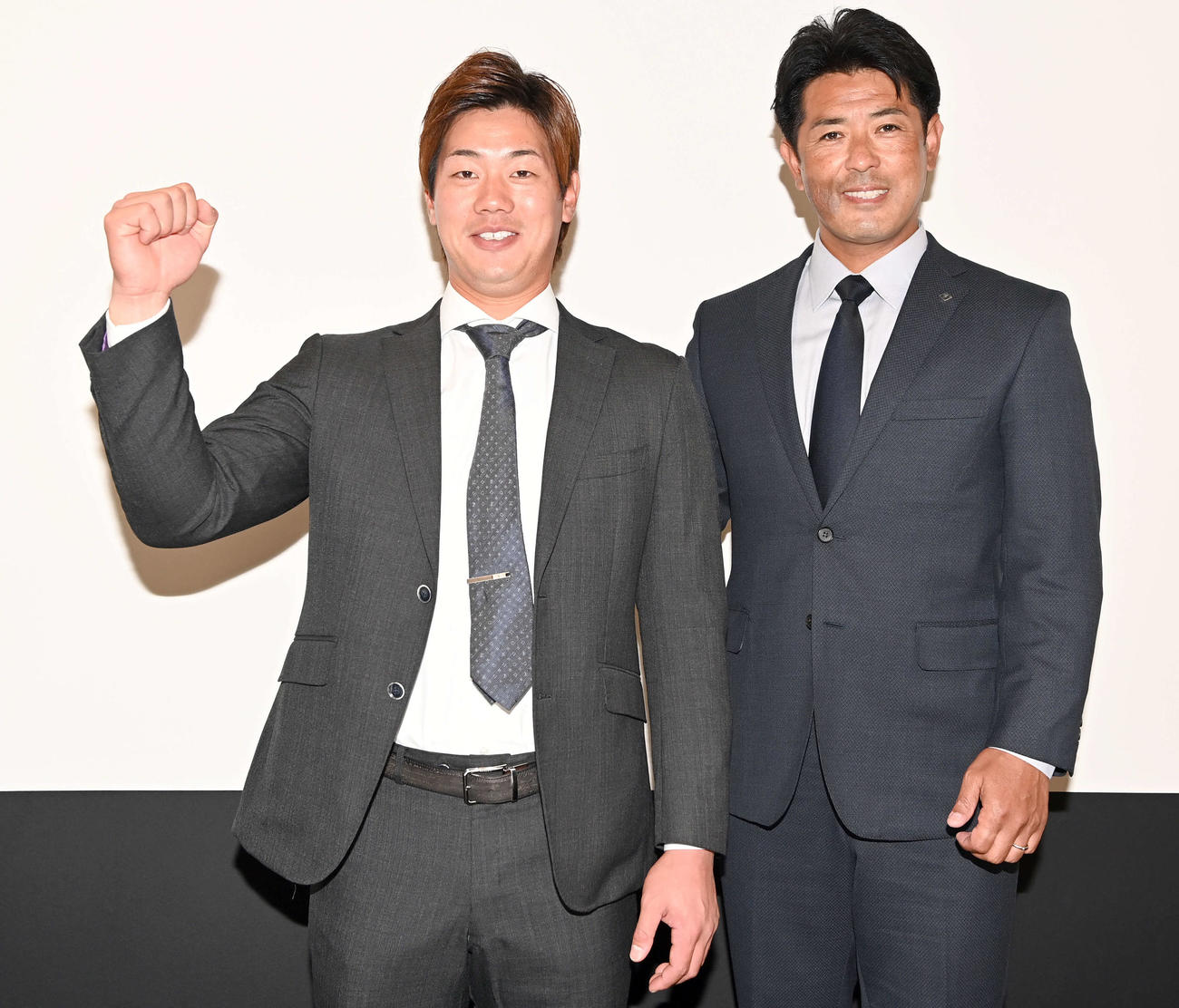 ロッテから移籍し笑顔でガッツポーズを決める日本ハム福田光。右は稲葉GM（撮影・たえ見朱実）