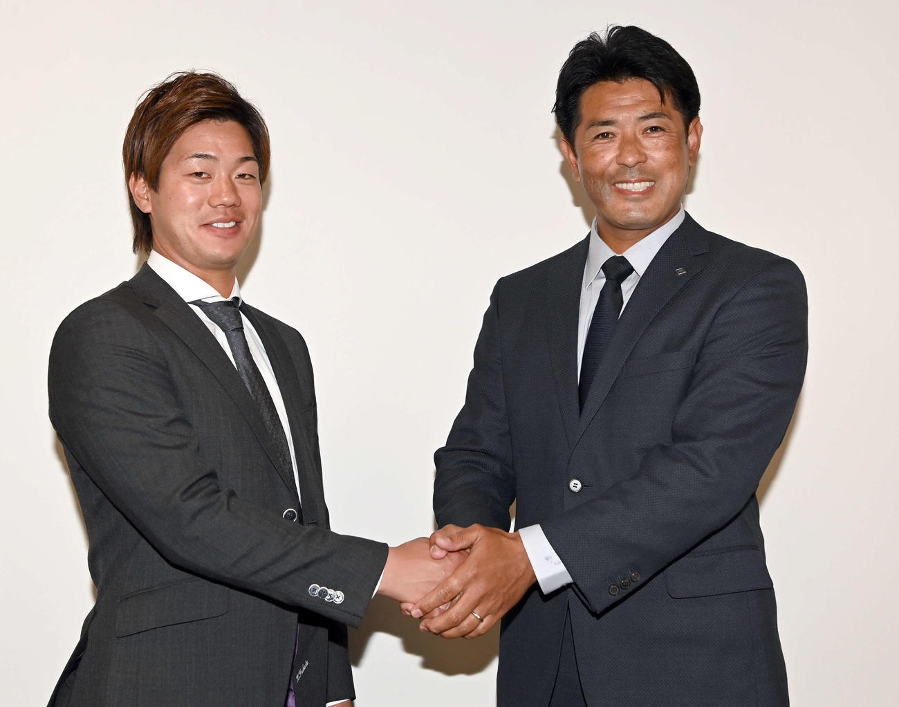 ロッテから移籍し稲葉篤紀GM（右）と握手を交わす日本ハム福田光（撮影・たえ見朱実）