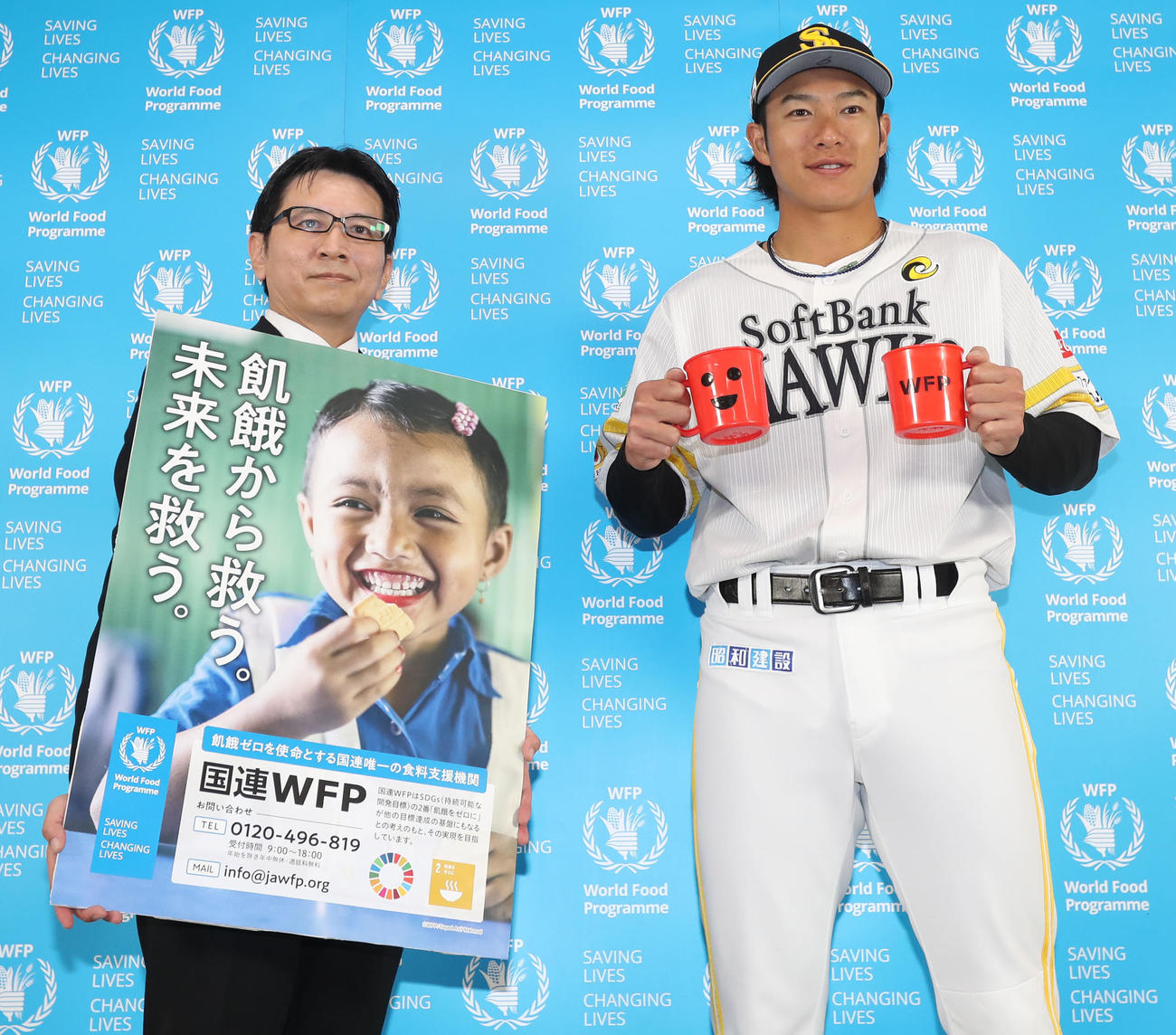 国連WFP協会事務局長青木氏（左）から感謝状を贈呈され、レッドカップを手に写真に納まる柳田（撮影・屋方直哉）