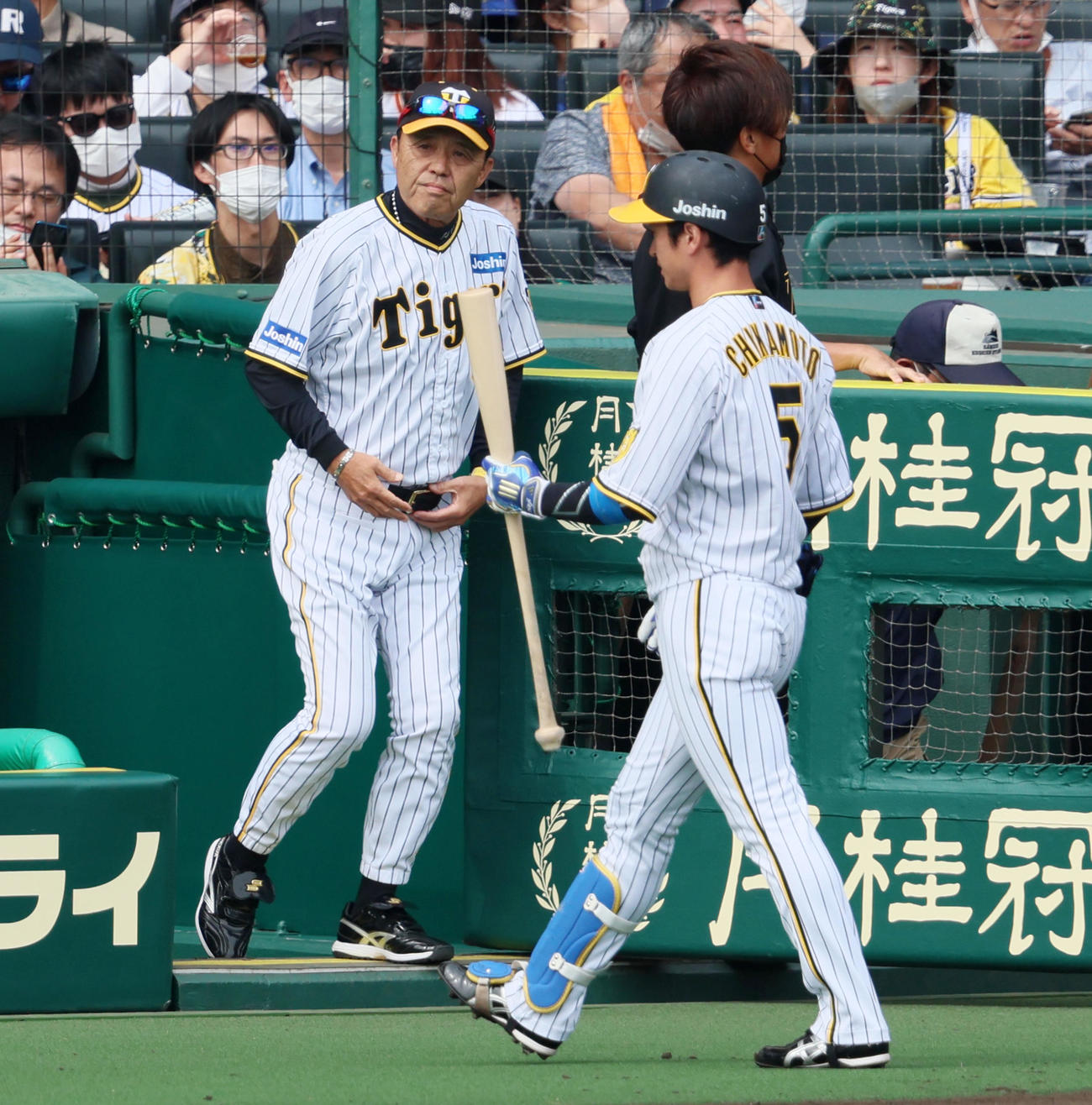 阪神対巨人　3回裏を終え選手交代を告げる岡田監督。右はベンチへ引き揚げる近本（撮影・加藤哉）