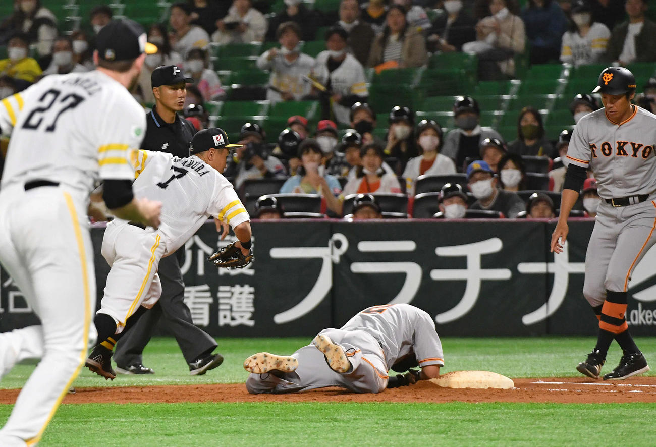 ソフトバンク対巨人　4回表巨人1死一塁、ガンケル（手前左）のけん制球が手に当たり、その場にうずくまる一塁走者の吉川（撮影・岩下翔太）