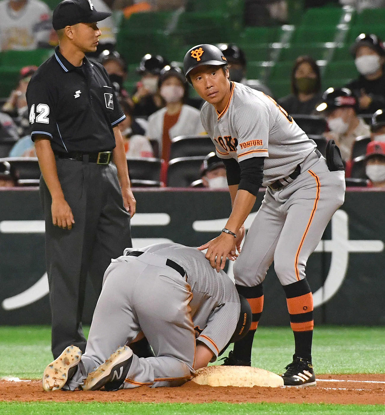 3月16日　ソフトバンク対巨人　4回表巨人1死一塁、ガンケルのけん制球が手に当たり、その場にうずくまる一塁走者の吉川（左）、右は鈴木コーチ